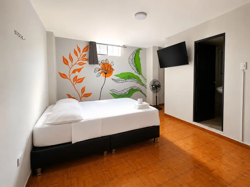 Suite King con mural de rama naranja y hoja verde, televisor y acceso al baño privado