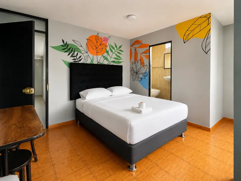 Mural de flores naranjas y hojas verdes junto a la puerta del baño, con escritorio de madera