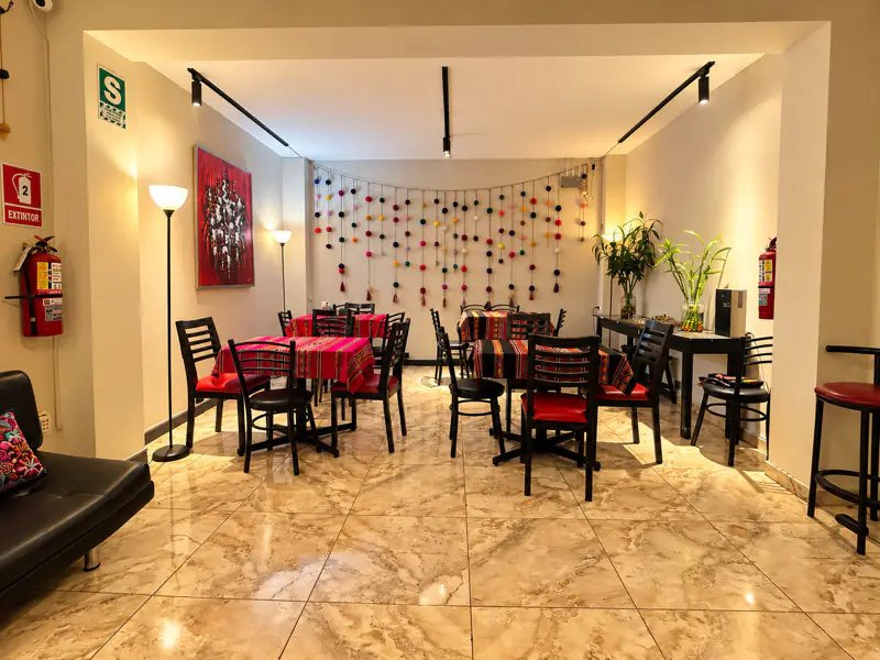 La sala vista desde la puerta de entrada, con las mesas reacomodables al centro y señalización de seguridad visible